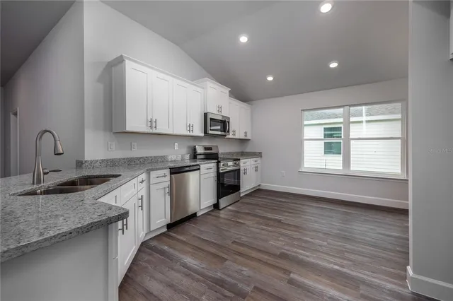 a kitchen with granite countertop white cabinets and white appliances
