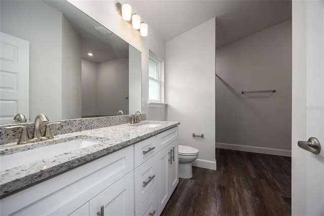 a bathroom with a granite countertop sink a toilet and a mirror