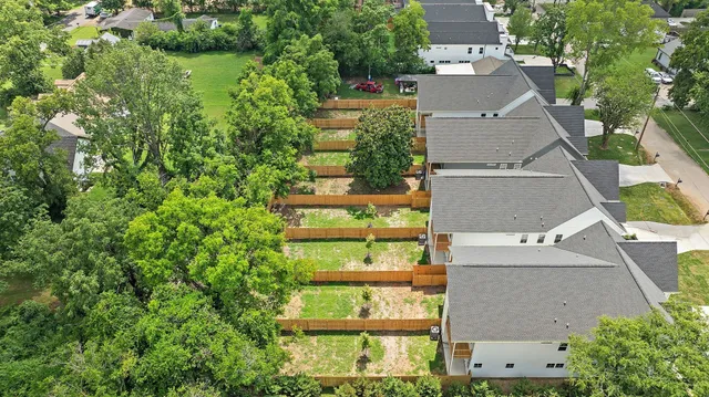 an aerial view of residential houses with outdoor space and trees