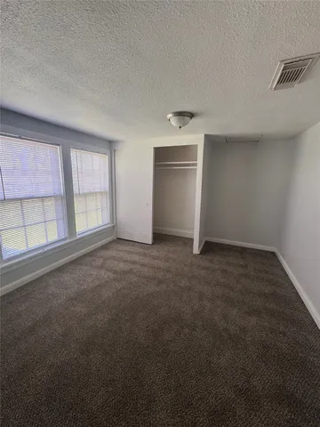 an empty room with chandelier fan and windows