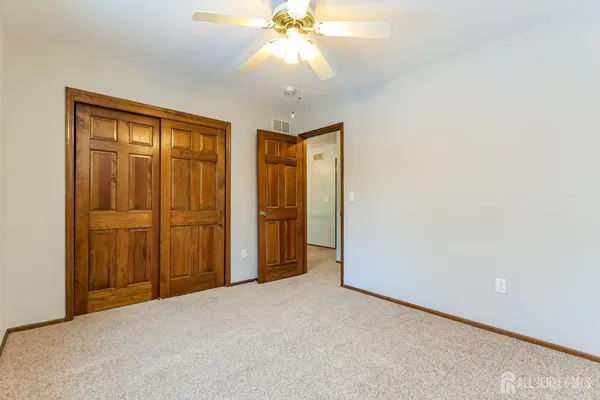 an empty room with windows and chandelier fan