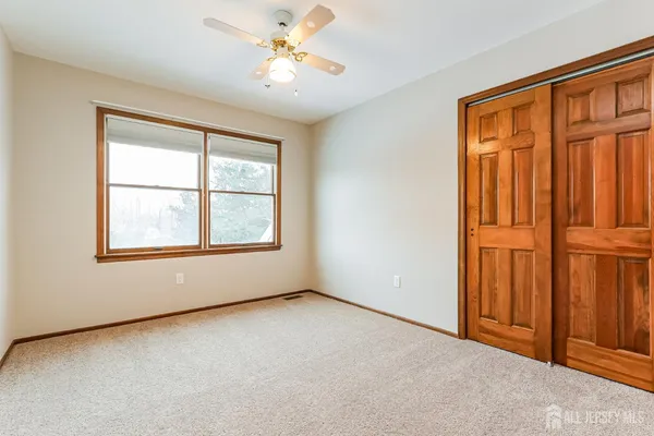 an empty room with windows closet and chandelier fan