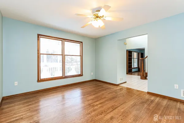 a view of an empty room with window and wooden floor