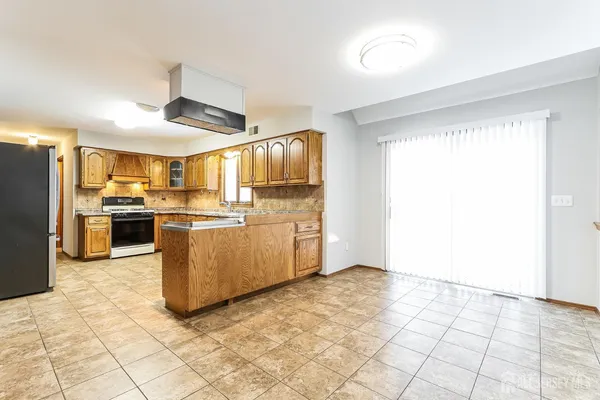 a kitchen with granite countertop a refrigerator and a stove top oven