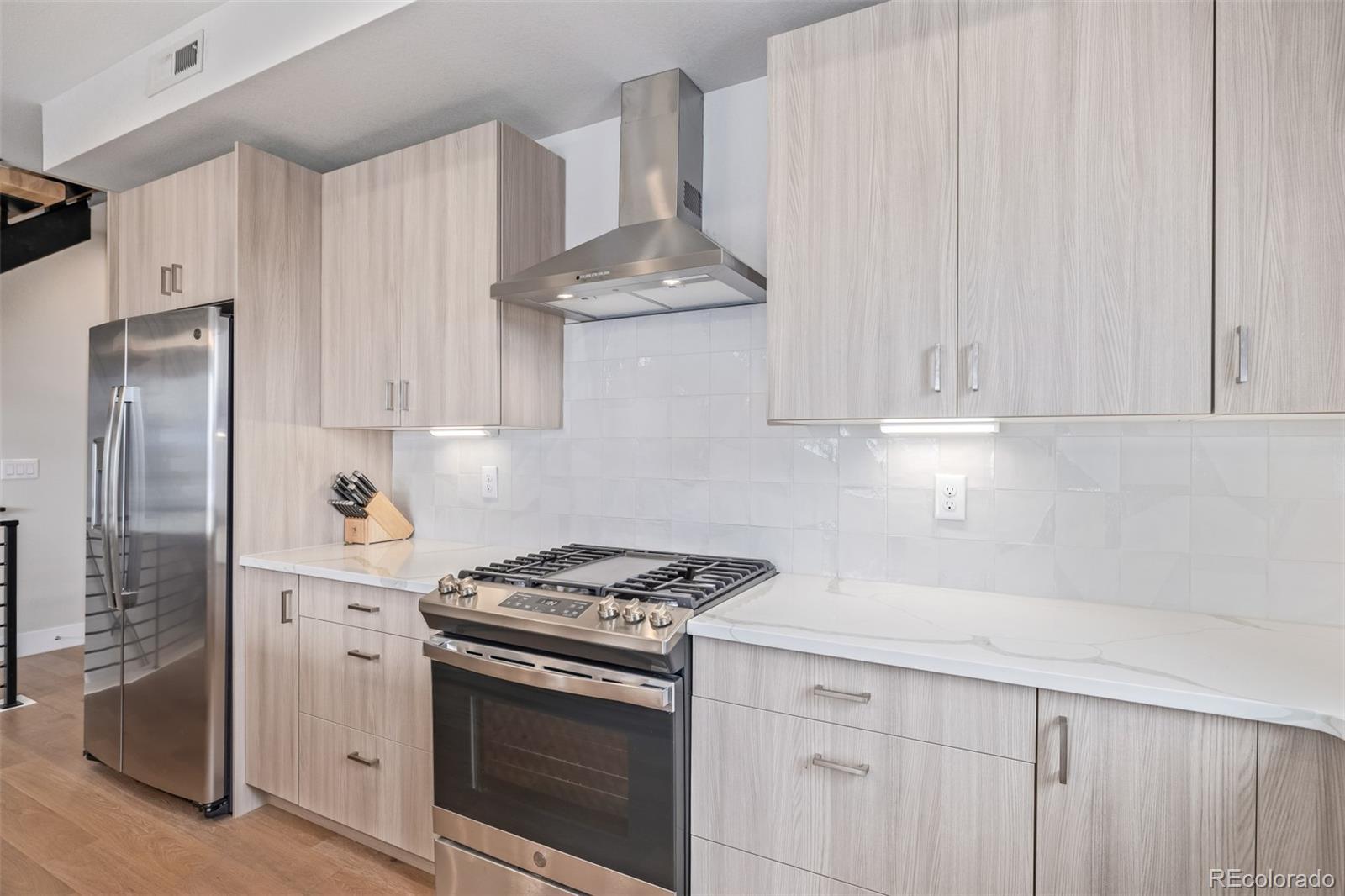 2350 Tremont Place, Unit 13 Denver, CO 80205 - Photo 13 of 41 a kitchen with stainless steel appliances white cabinets and a stove