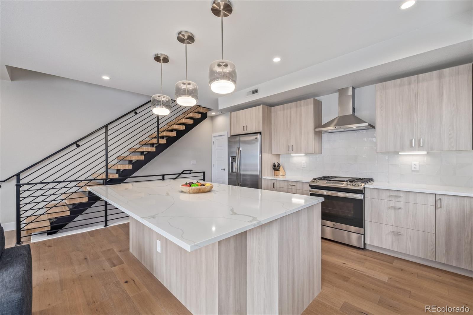 2350 Tremont Place, Unit 13 Denver, CO 80205 - Photo 2 of 41 a kitchen with a stove a chandelier and wooden floor