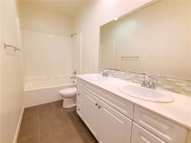 a bathroom with a granite countertop sink toilet a large mirror and bathtub