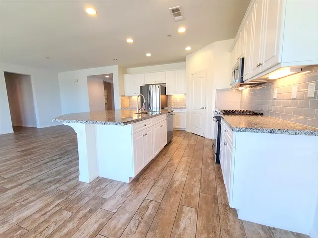 a kitchen with stainless steel appliances a stove top oven a sink and a refrigerator