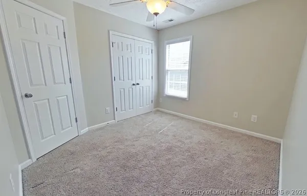 an empty room with windows and a chandelier fan