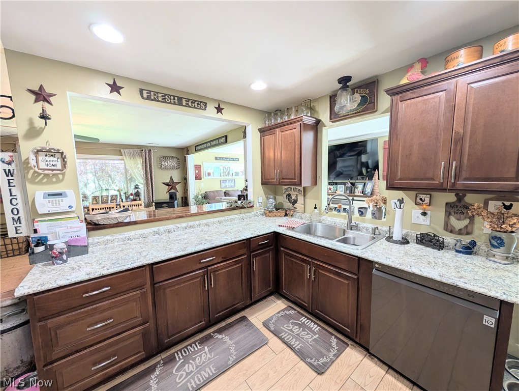 6700 McCaslin Road Nashport, OH 43830 - Photo 19 of 30 Kitchen featuring wood-finish flooring, dark wood cabinetry, light-toned countertops, a stainless steel double basin sink with a gooseneck faucet, and a built-in stainless steel dishwasher