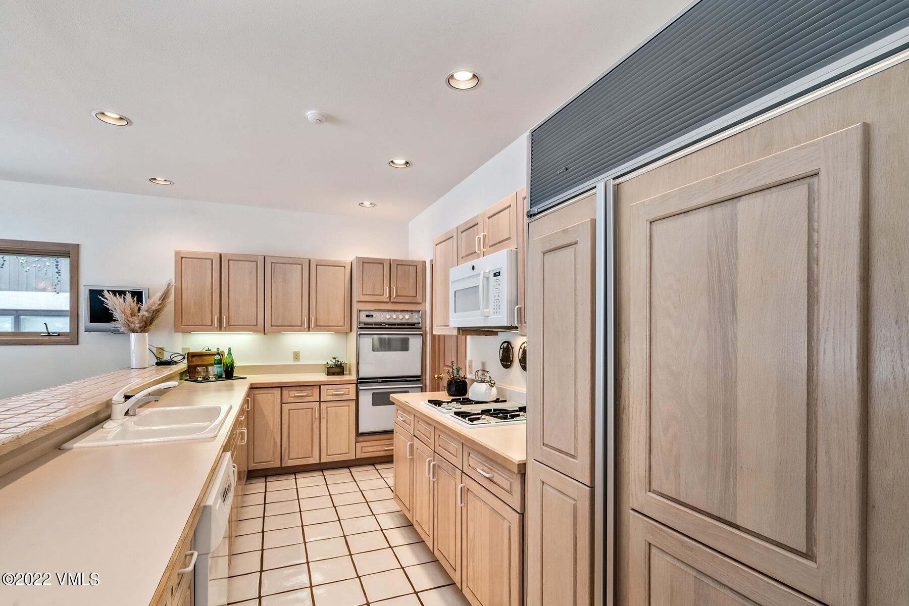 3984 Big Horn Road, Unit A Vail, CO 81657 - Photo 23 of 50 a kitchen with stainless steel appliances granite countertop a refrigerator a sink dishwasher and white cabinets with wooden floor