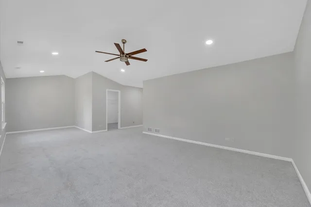 an empty room with windows and ceiling fan