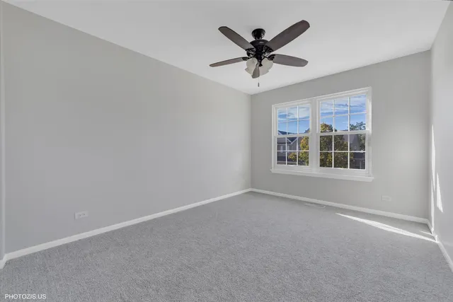 an empty room with a window and ceiling fan