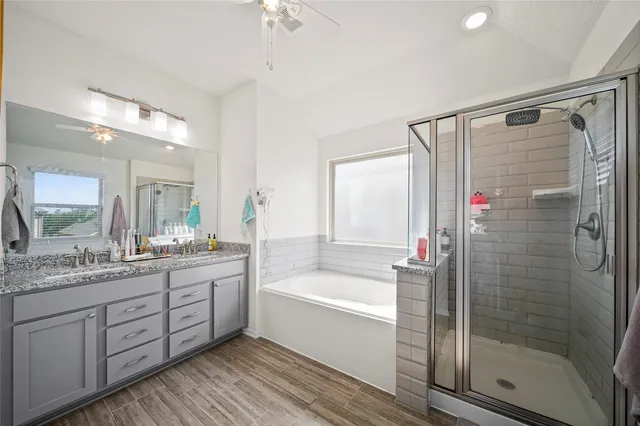 a bathroom with a granite countertop sink a mirror a bathtub and shower