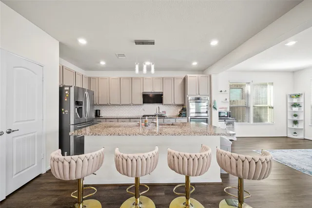 a kitchen with stainless steel appliances kitchen island granite countertop a refrigerator and chairs