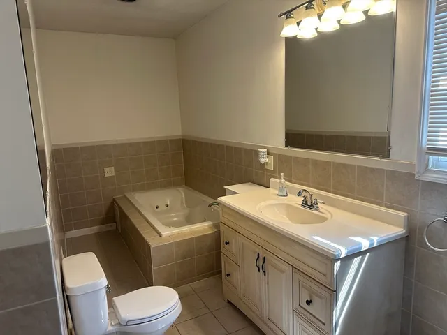 a bathroom with a sink toilet vanity and tub
