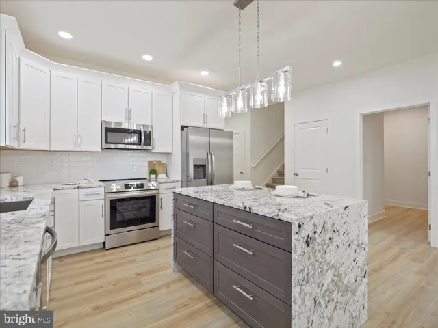 a kitchen with stainless steel appliances granite countertop a sink a stove a refrigerator and a oven with wooden floor