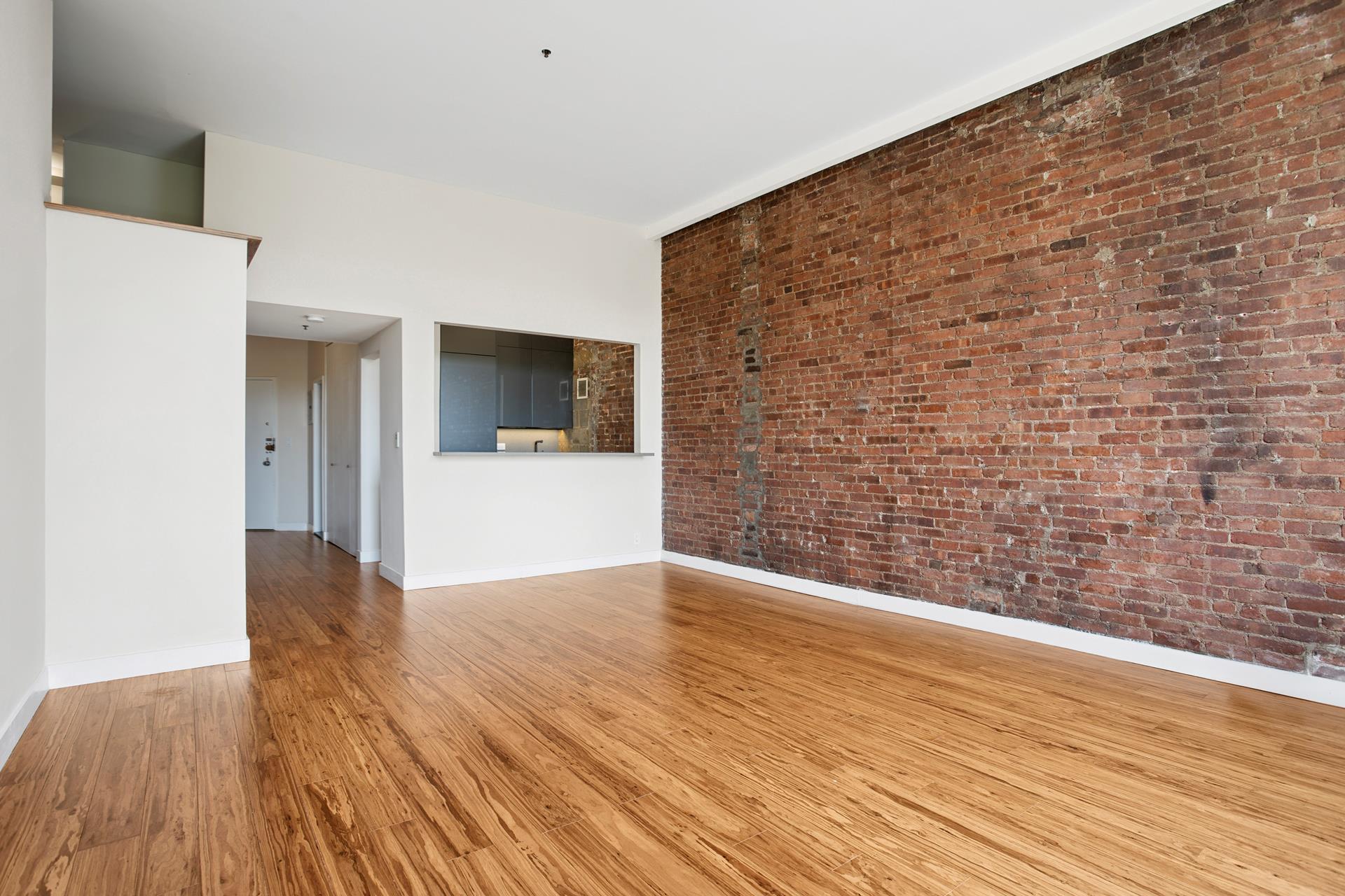 77 Bleecker Street, Unit 804 Manhattan, NY 10012 - Photo 5 of 12 a view of an empty room with wooden floor and a kitchen