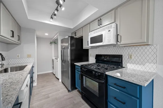 a kitchen with granite countertop a sink stove and cabinets