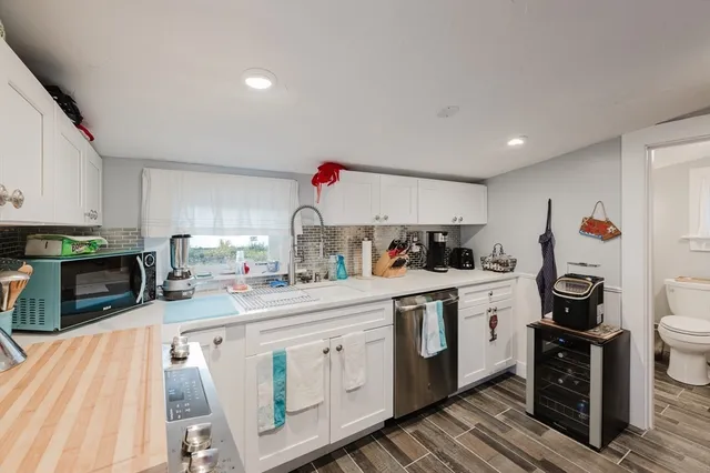 a kitchen with stainless steel appliances granite countertop a stove a sink dishwasher and white cabinets with wooden floor