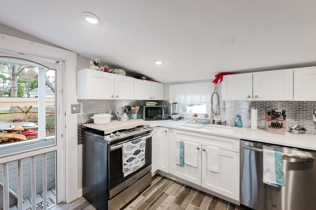 4 Ross Avenue Wareham, MA 02571 - Photo 29 of 39 a kitchen with stainless steel appliances granite countertop a stove a sink dishwasher and white cabinets with wooden floor