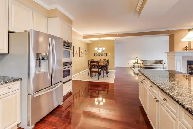 a kitchen with stainless steel appliances granite countertop a refrigerator a stove and a wooden floors