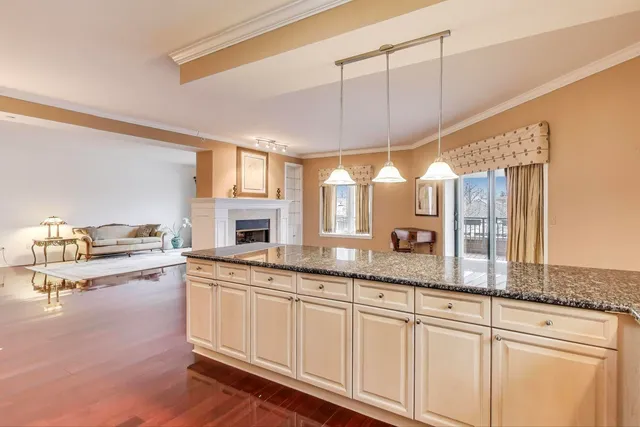 a large white kitchen with granite countertop a sink and white cabinets next to a window