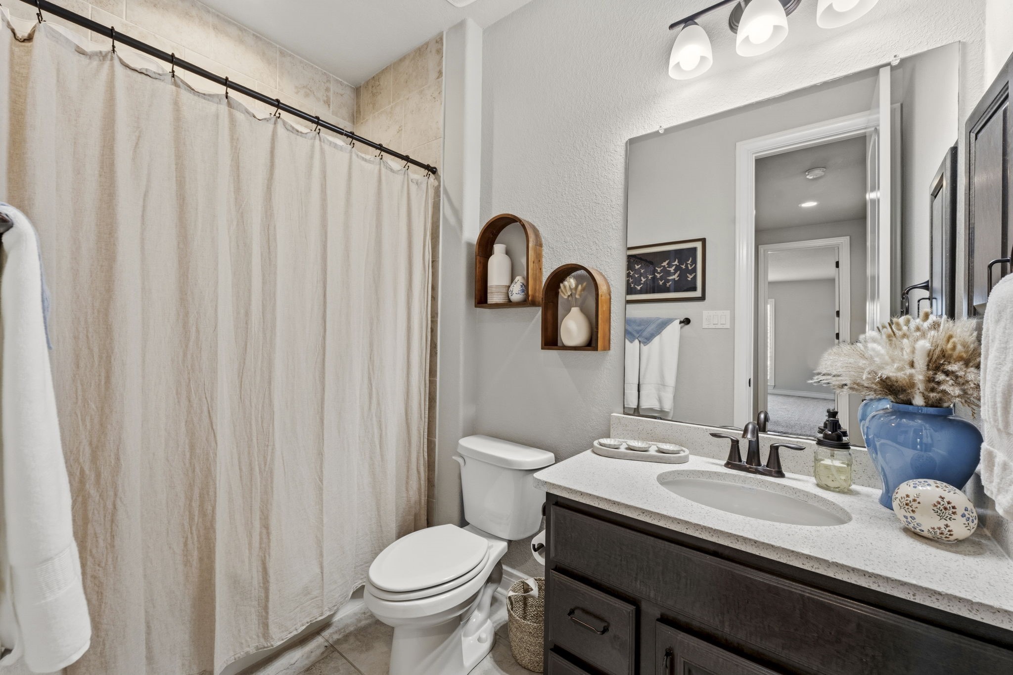 14012 Beartooth Bend Trail Conroe, TX 77384 - Photo 26 of 50 The full bathroom for Bedrooms 2 and 3 features tile flooring, single sink with quartz countertop and oval undermount sink, medicine cabinet, hall linen closet, toilet, and tiled shower/tub with dual built-in toiletry niches.