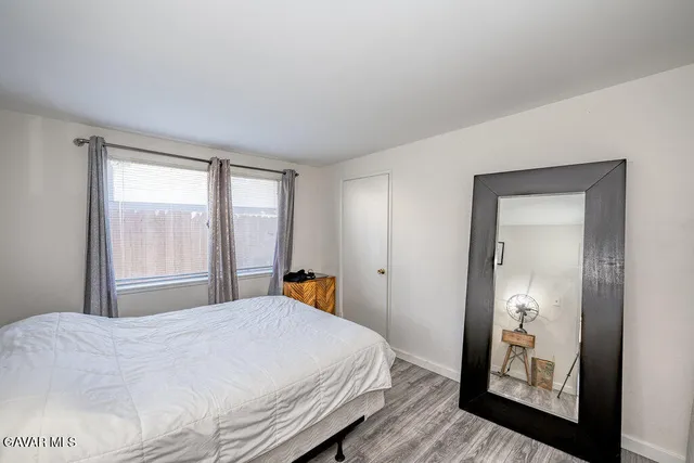 a bedroom with a bed and a large mirror next to a window