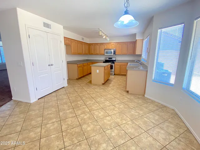 a kitchen with stainless steel appliances granite countertop a sink a stove a refrigerator cabinets and a window