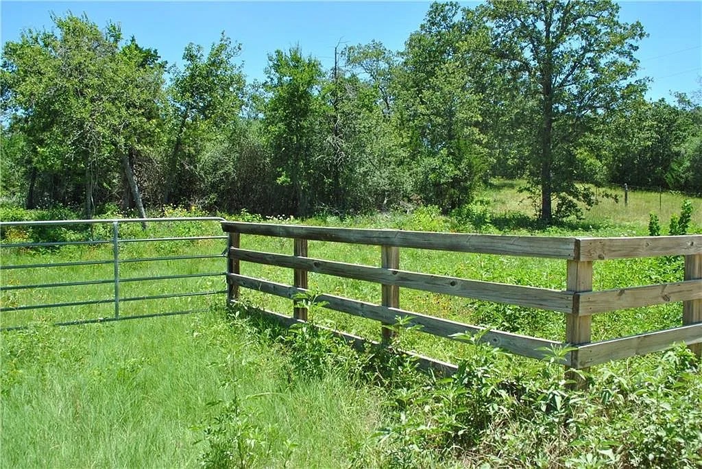 21741 East Interstate 10 Luling, TX 78648 - Photo 8 of 11 A rustic wooden fence and metal gate define the boundaries of this verdant, treed lot.