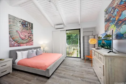 a bedroom with a bed painting on wall and a potted plant