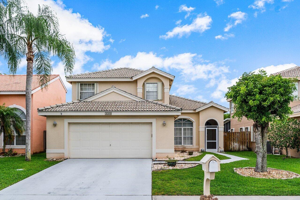 7250 Davit Circle Lake Worth, FL 33467 - Photo 1 of 35 a front view of a house with a garden and trees