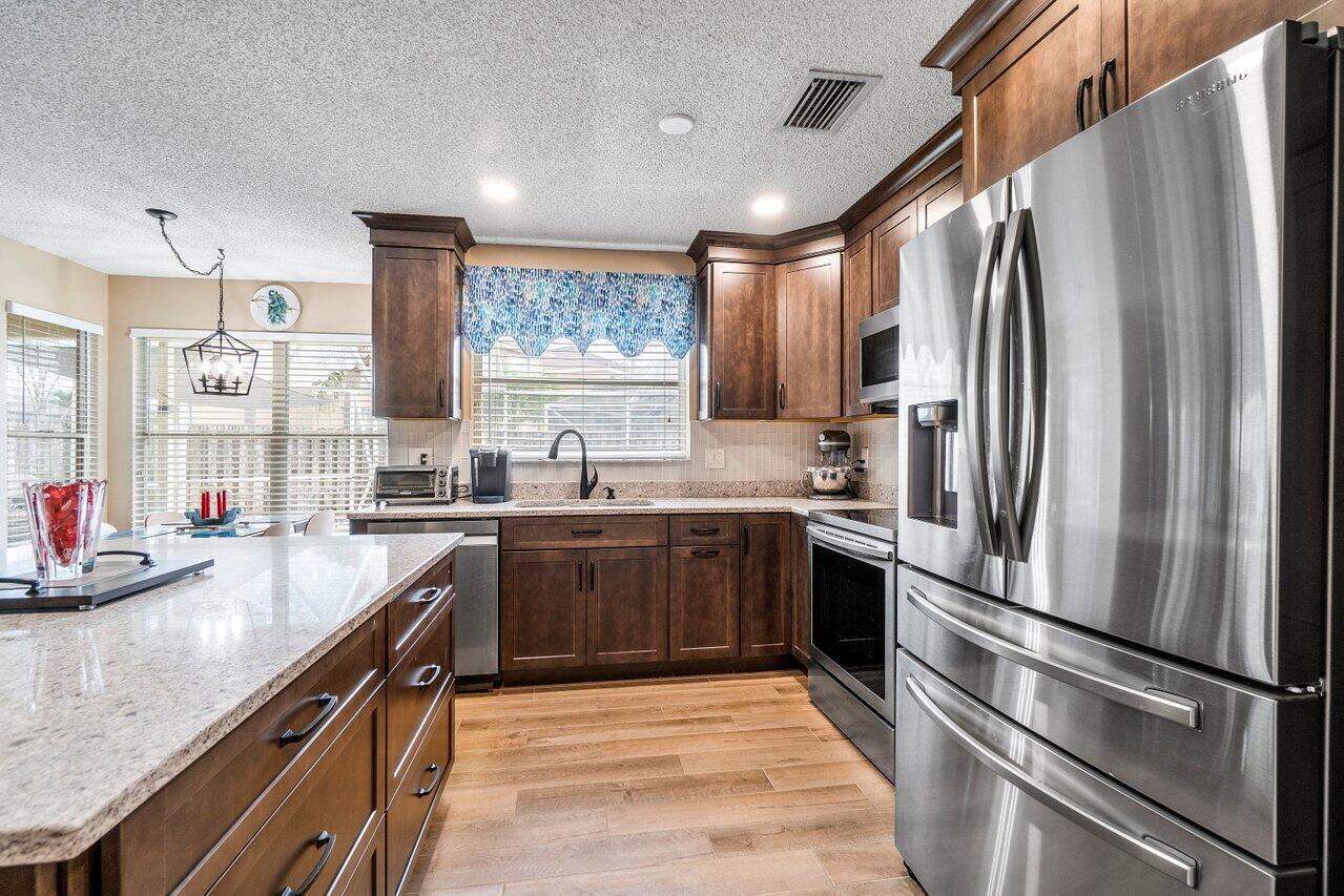 7250 Davit Circle Lake Worth, FL 33467 - Photo 12 of 35 a kitchen with stainless steel appliances granite countertop a refrigerator a sink dishwasher a stove top oven a refrigerator and cabinets
