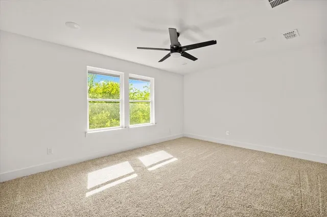 an empty room with a window and a ceiling fan