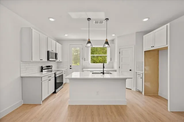 a kitchen with stainless steel appliances granite countertop a sink a stove a refrigerator and island with wooden floor