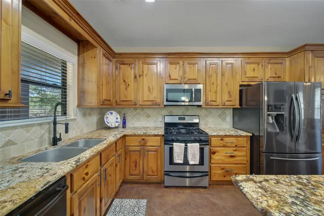 a dining hall with stainless steel appliances granite countertop a stove a sink a dining table and chairs with wooden floor