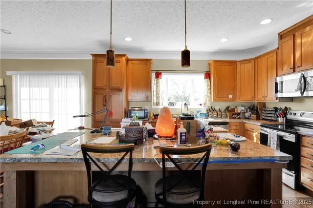 a view of a kitchen with stainless steel appliances granite countertop a refrigerator a stove top oven a sink dishwasher and wooden cabinets