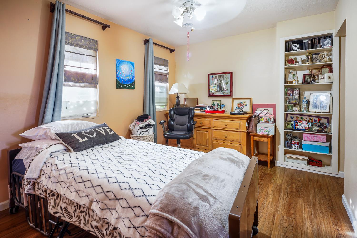 23404 Bruella Road Acampo, CA 95220 - Photo 39 of 69 a bedroom with a bed and a bookshelf with wooden floor