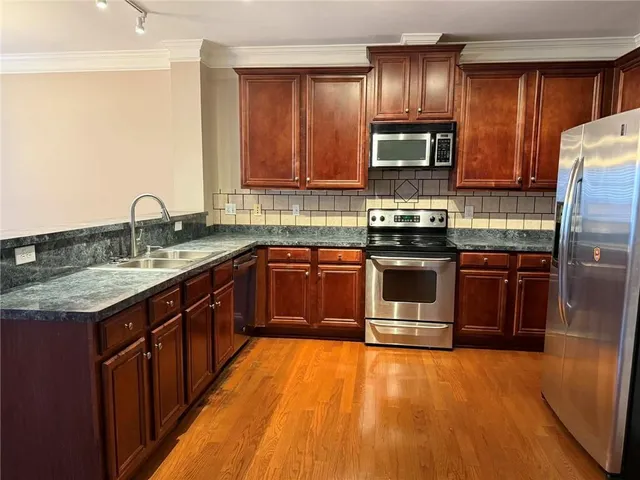 a large kitchen with stainless steel appliances granite countertop a stove refrigerator and a sink