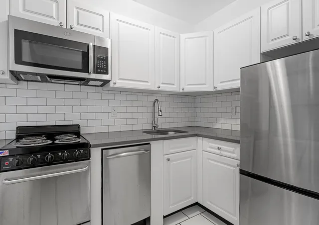 a kitchen with cabinets stainless steel appliances and sink
