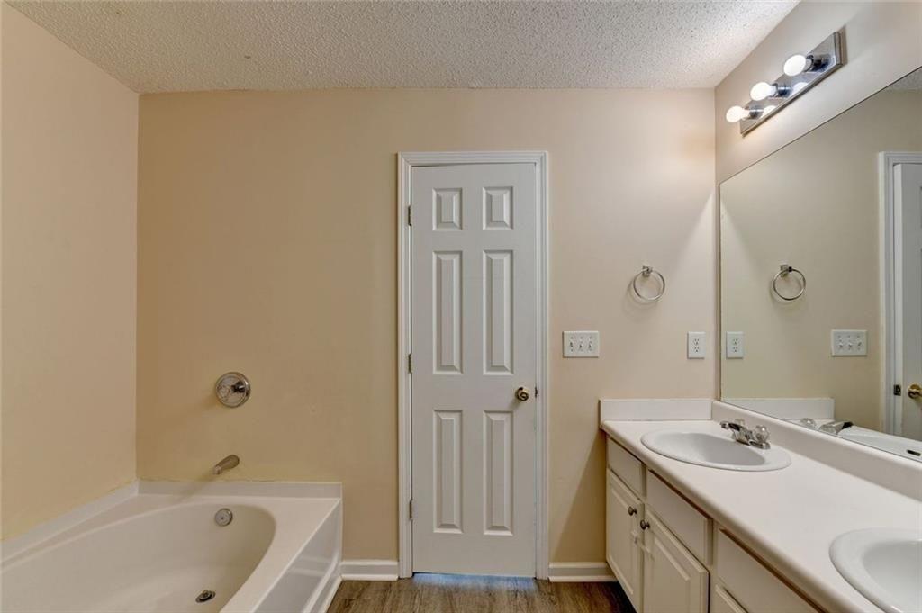 310 Azalea Circle Cumming, GA 30040 - Photo 22 of 38 a bathroom with a tub sink vanity granite and a mirror