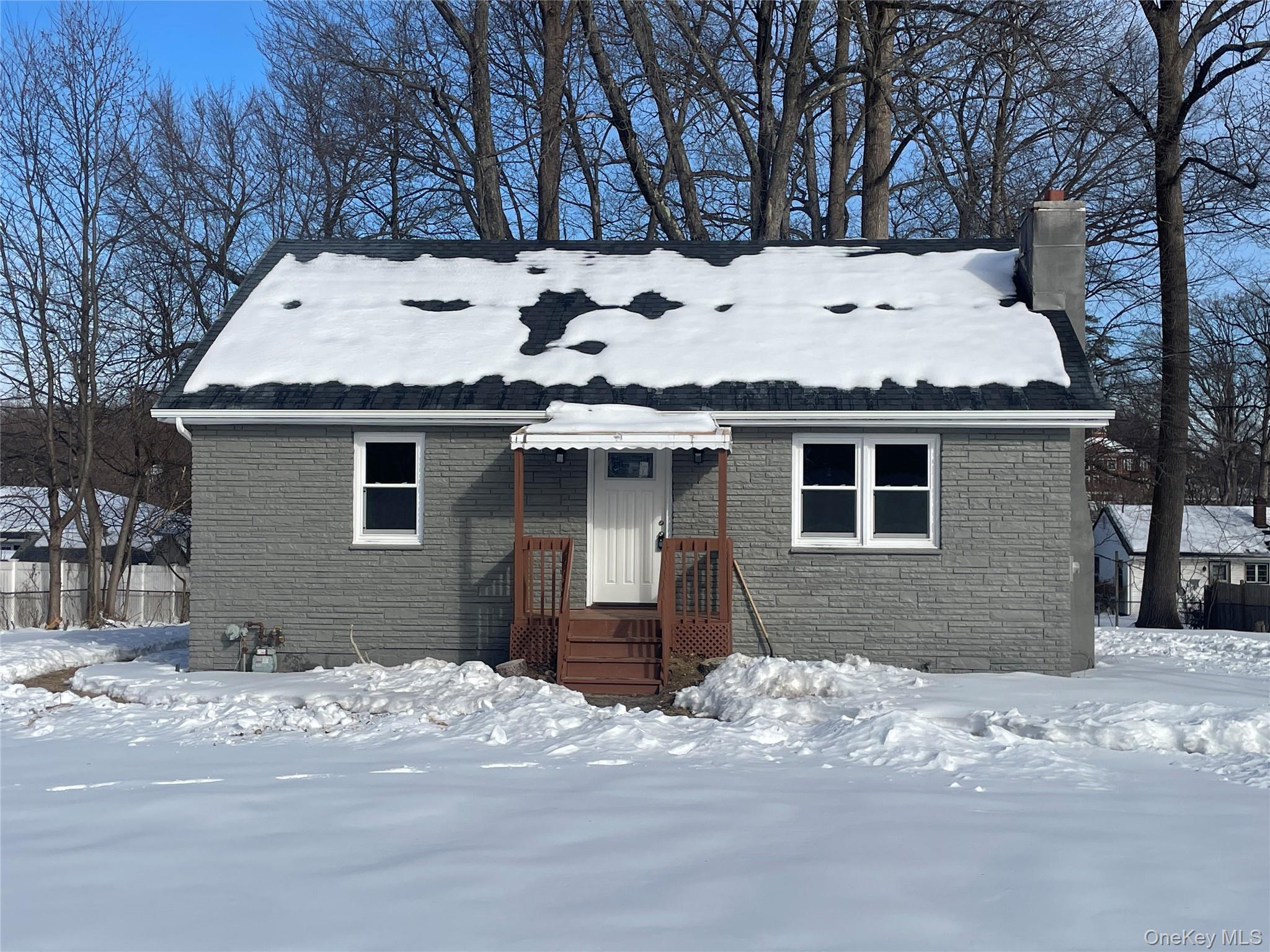 View of front of house featuring a chimney and brick siding