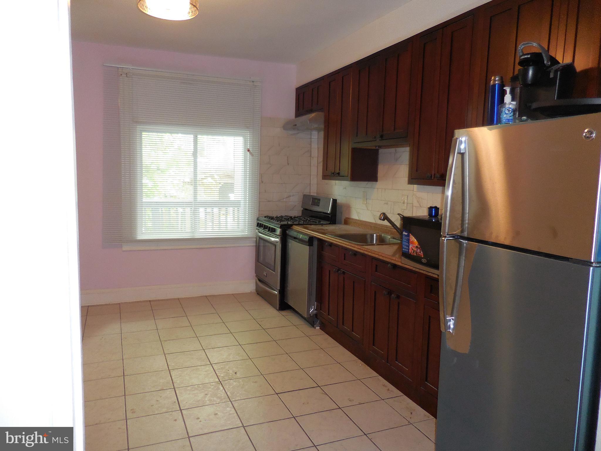 603 East 36th Street Baltimore, MD 21218 - Photo 7 of 29 a kitchen with a refrigerator a stove a sink and a window