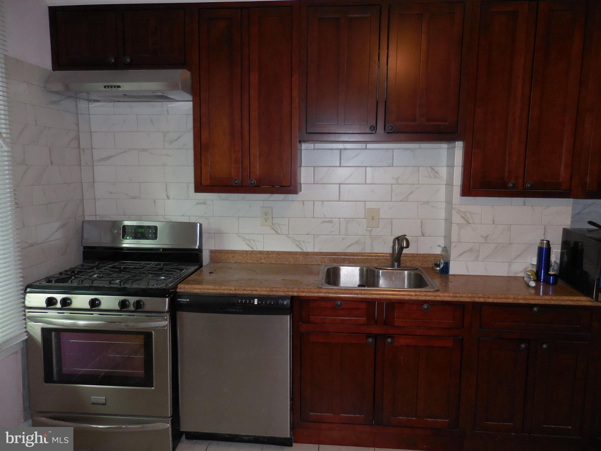 603 East 36th Street Baltimore, MD 21218 - Photo 9 of 29 a kitchen with granite countertop wooden cabinets and a stove top oven