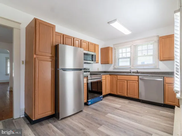 a kitchen with stainless steel appliances granite countertop a refrigerator a sink dishwasher a stove with wooden floor and cabinets