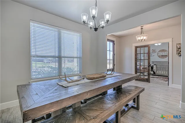 a dining room with wooden floor and chandelier
