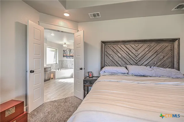 a bedroom with a large bed a couch and a view of kitchen