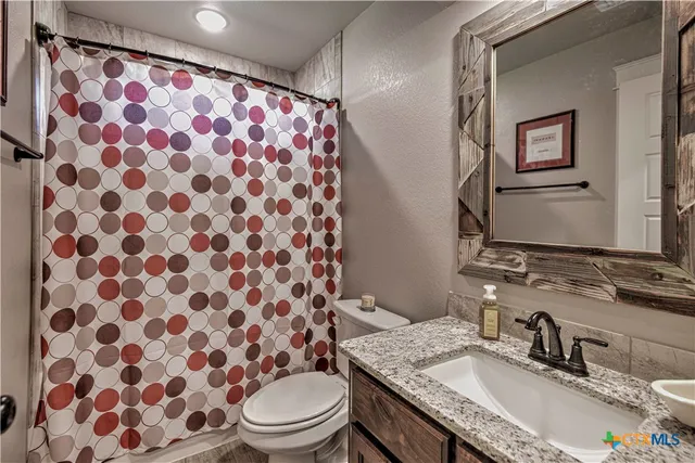a bathroom with a granite countertop toilet a sink and a mirror