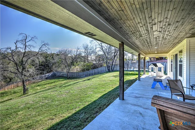 a view of a backyard with couches plants and large trees